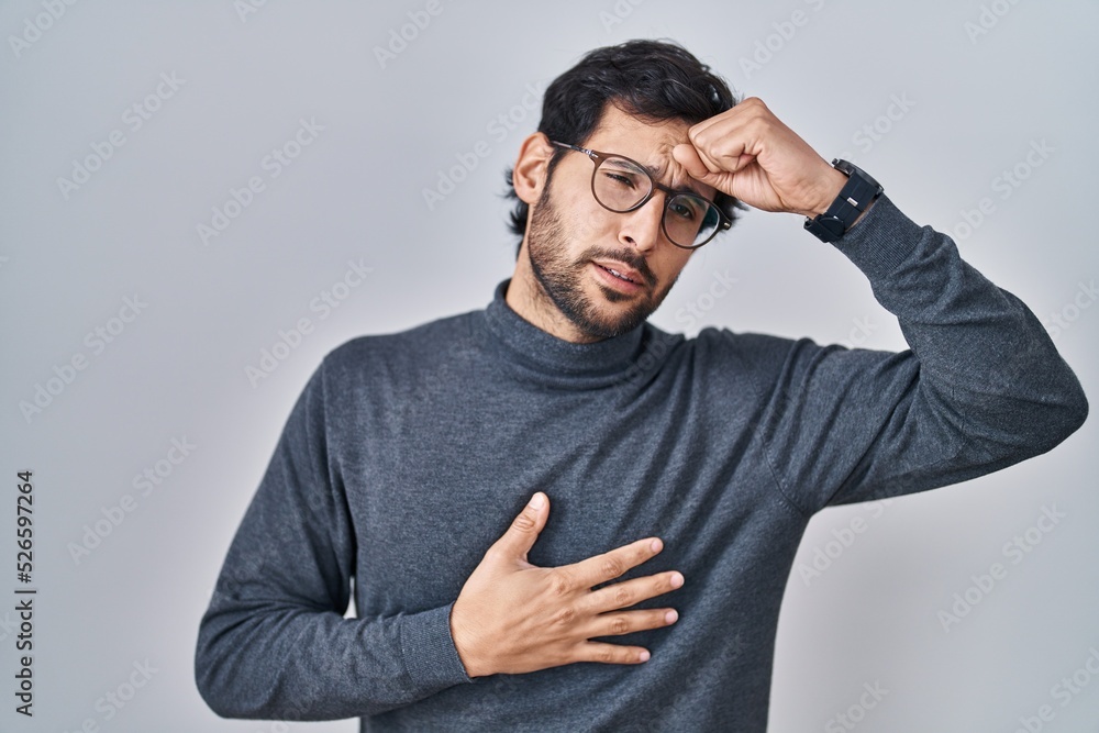 Handsome latin man standing over isolated background touching forehead for illness and fever, flu and cold, virus sick Handsome latin man standing over isolated background touching forehead for illness and fever, flu and cold, virus sick