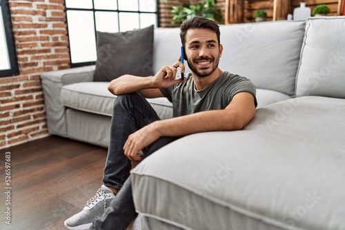 Young hispanic man smiling confident talking on the smartphone at home