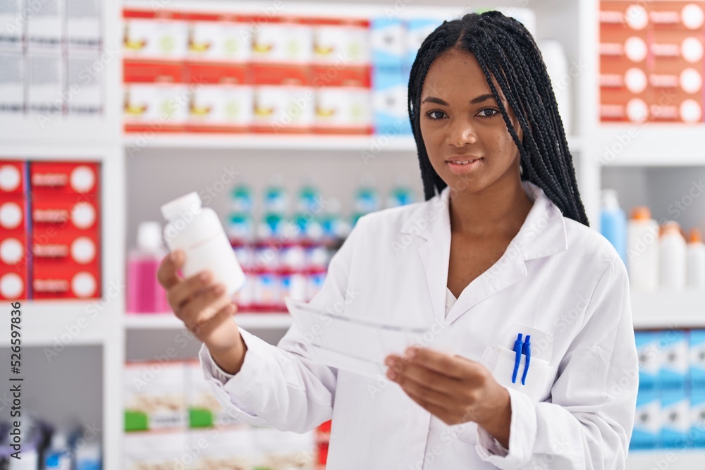 African american woman pharmacist holding pills bottle reading prescription at pharmacy African american woman pharmacist holding pills bottle reading prescription at pharmacy