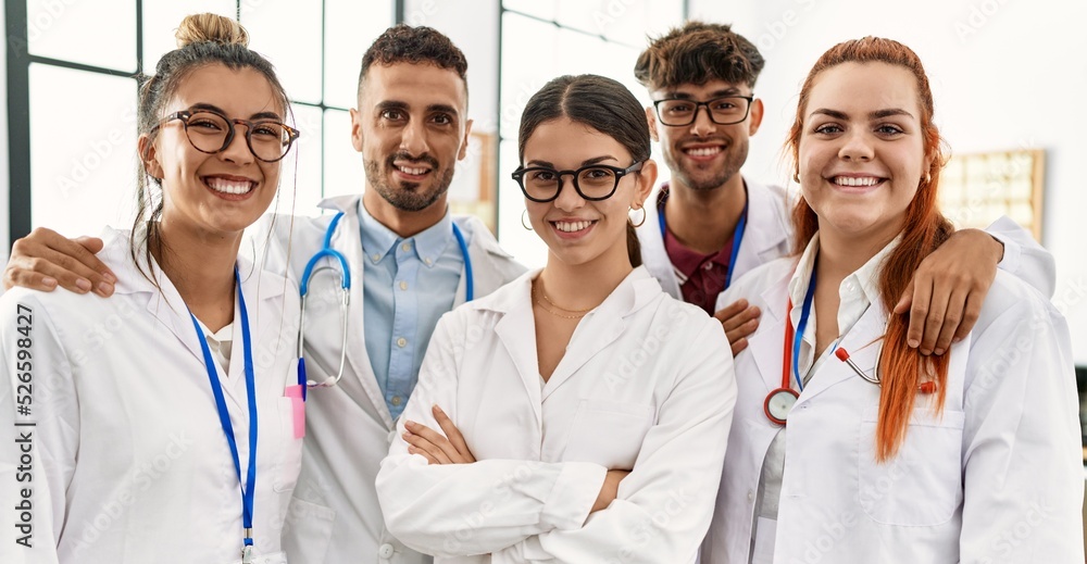 Group of young doctor smiling happy and hugging standing at the clinic office. Group of young doctor smiling happy and hugging standing at the clinic office.