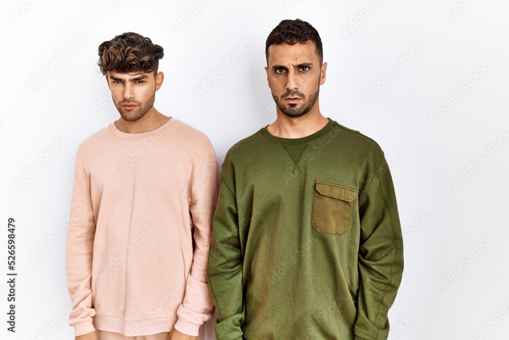 Young gay couple standing over isolated white background skeptic and nervous, frowning upset because of problem. negative person. Young gay couple standing over isolated white background skeptic and nervous, frowning upset because of problem. negative person.