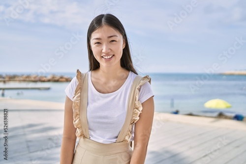 Young chinese girl smiling happy standing at the beach.