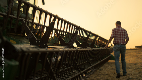 Fotografie Rancher check field thresher reel farming vehicle at golden sunset countryside