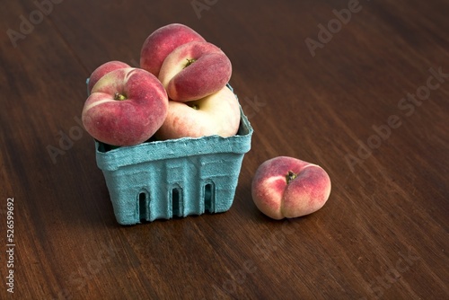 Pint of white donut peaches on rustic wooden table