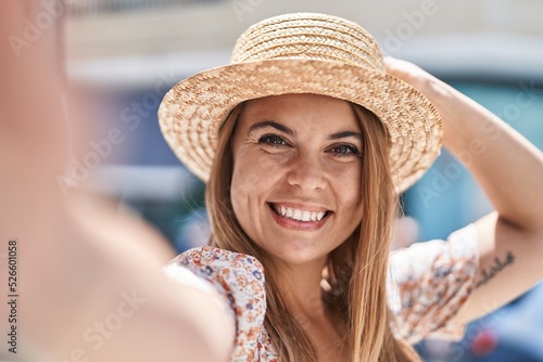 Young woman tourist wearing summer hat make selfie by camera at street