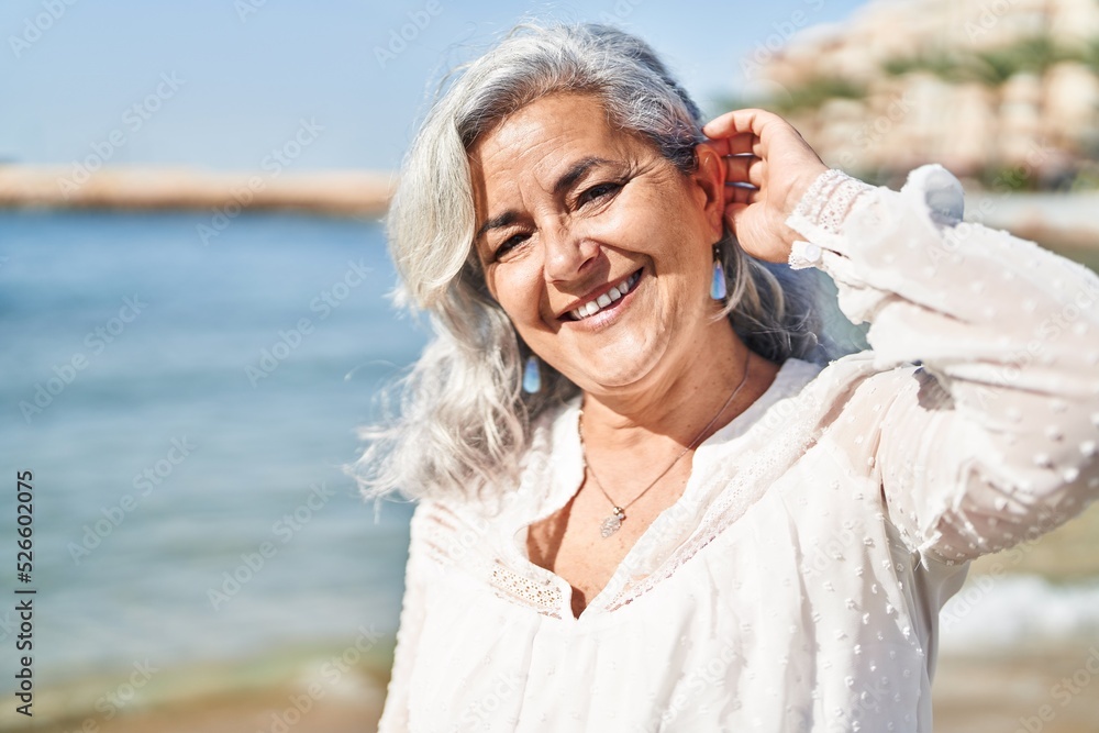 Middle age woman smiling confident standing at seaside