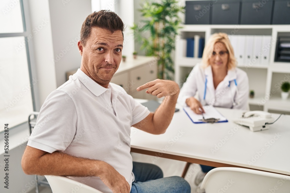Hispanic man at the doctor pointing finger to one self smiling happy and proud Hispanic man at the doctor pointing finger to one self smiling happy and proud