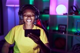 African american woman playing video games with smartphone looking positive and happy standing and smiling with a confident smile showing teeth