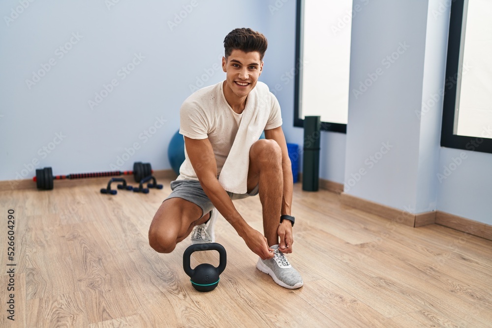 Young hispanic man smiling confident tying shoes at sport center Young hispanic man smiling confident tying shoes at sport center