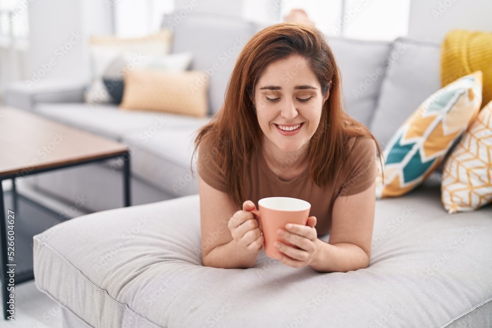 Young woman drinking coffee lying on sofa at home Young woman drinking coffee lying on sofa at home