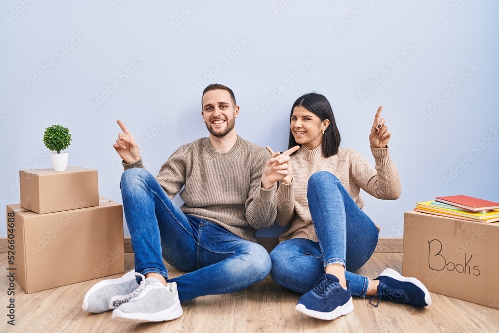 Young couple moving to a new home smiling confident pointing with fingers to different directions. copy space for advertisement Young couple moving to a new home smiling confident pointing with fingers to different directions. copy space for advertisement