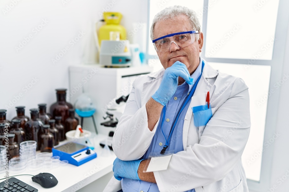 Middle age grey-haired man wearing scientist uniform with arms crossed gesture at laboratory Middle age grey-haired man wearing scientist uniform with arms crossed gesture at laboratory