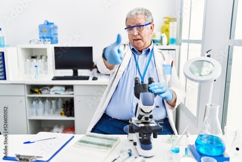 Senior caucasian man working at scientist laboratory pointing fingers to camera with happy and funny face. good energy and vibes.