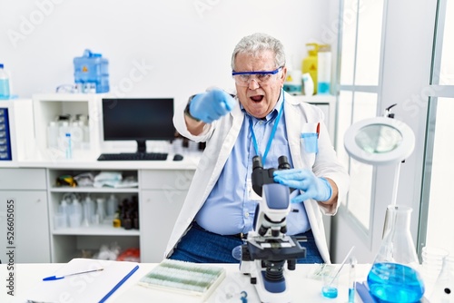 Senior caucasian man working at scientist laboratory pointing displeased and frustrated to the camera, angry and furious with you
