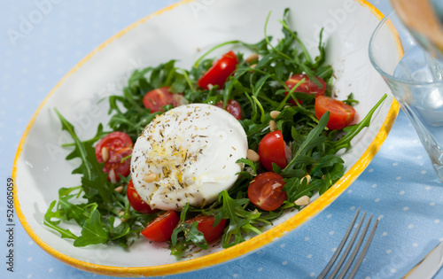 Plate of tasty fresh salad with Burrata cheese, tomatoes and arugula