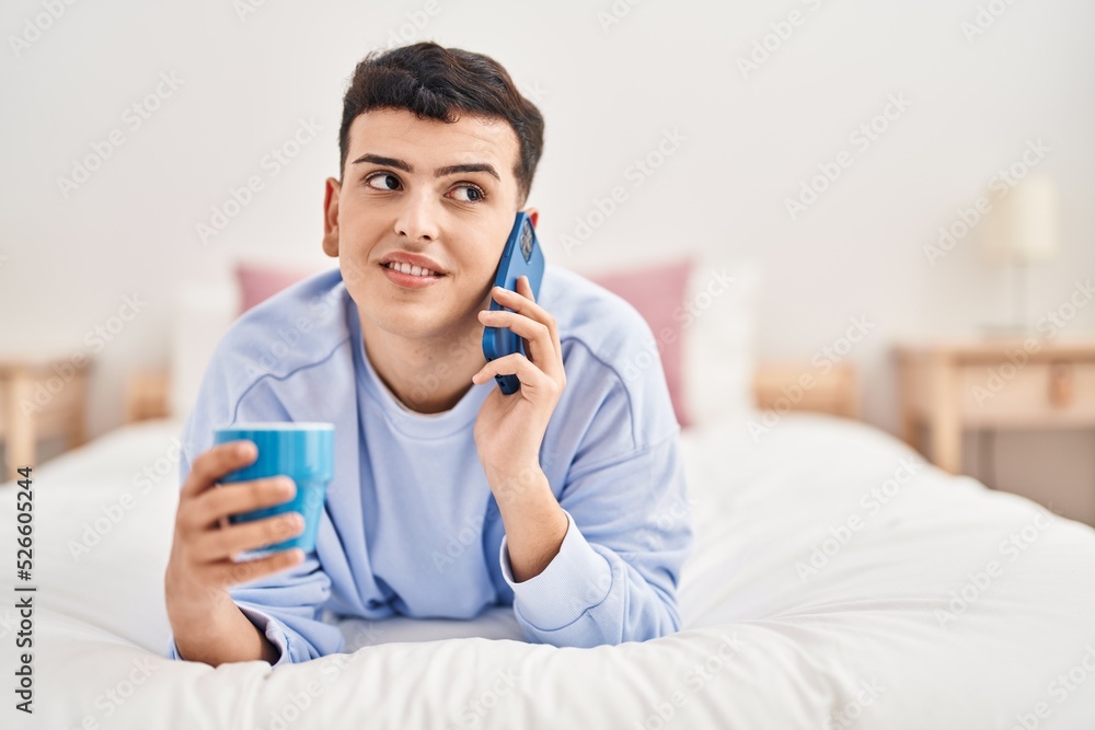 Young non binary man talking on the smartphone drinking coffee Young non binary man talking on the smartphone drinking coffee
