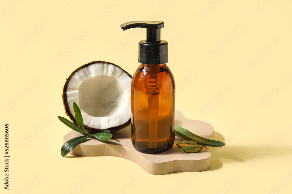 Bottle of natural cosmetic product and coconut on color background Bottle of natural cosmetic product and coconut on color background