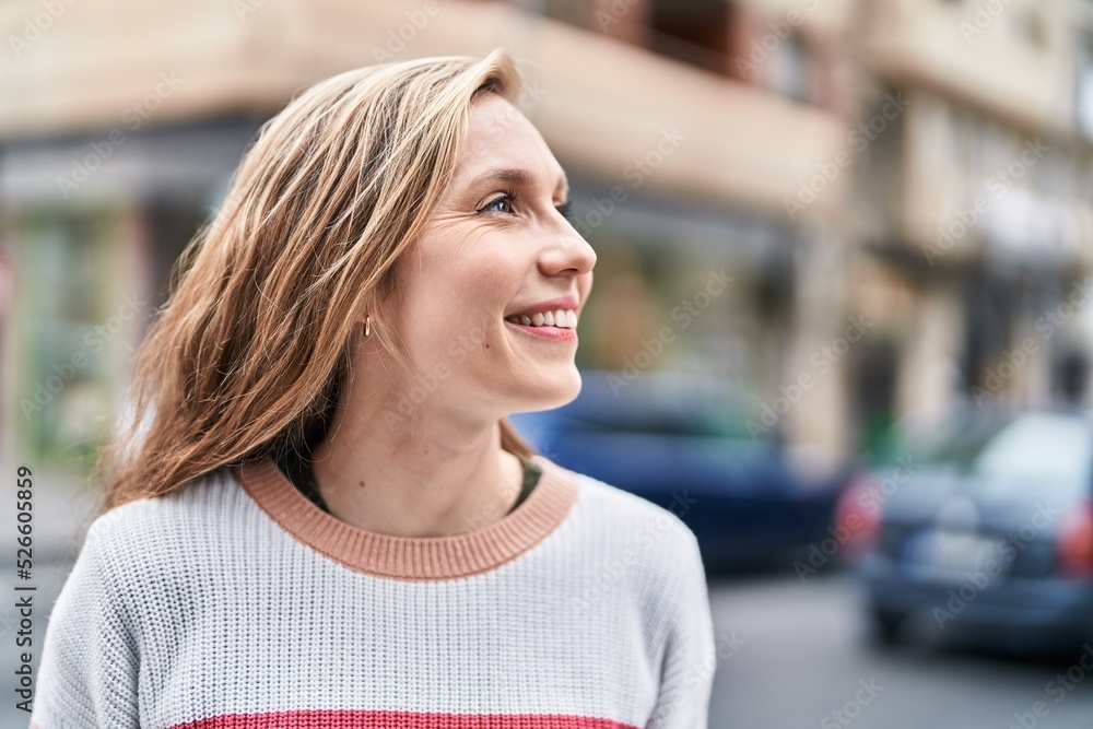 Young blonde woman smiling confident looking to the side at street