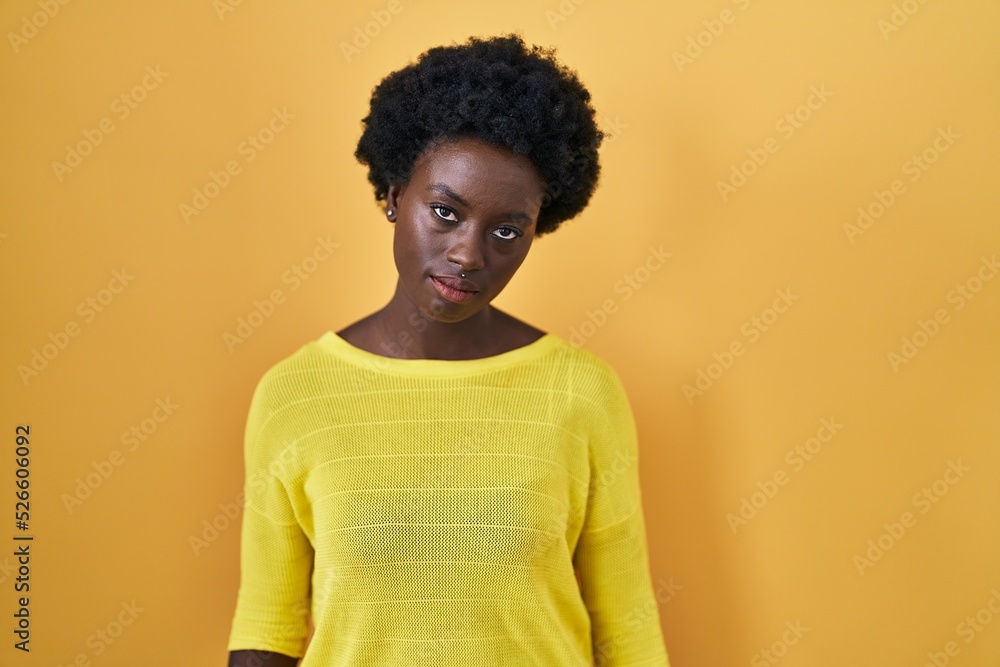 Fototapeta premium African young woman standing over yellow studio looking sleepy and tired, exhausted for fatigue and hangover, lazy eyes in the morning.