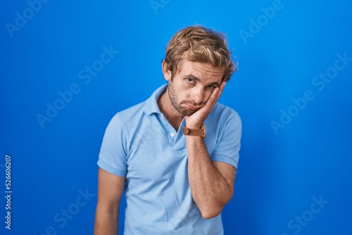 Caucasian man standing over blue background thinking looking tired and bored with depression problems with crossed arms.