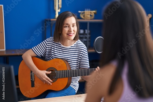 Two women musicians playing classical guitar and piano at music studio
