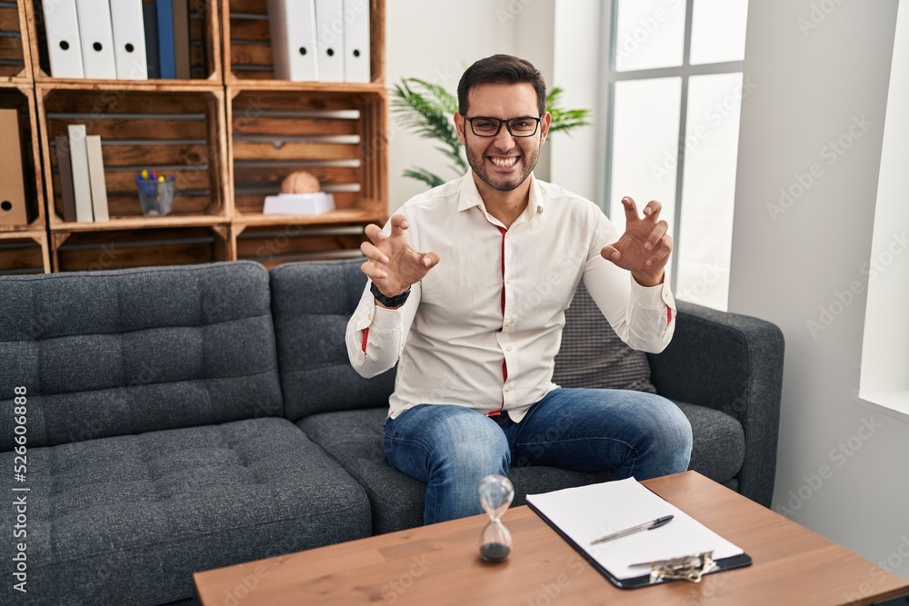 Young hispanic man with beard working at consultation office smiling funny doing claw gesture as cat, aggressive and sexy expression Young hispanic man with beard working at consultation office smiling funny doing claw gesture as cat, aggressive and sexy expression