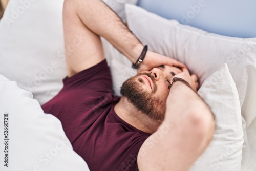 Young hispanic man suffering insomnia lying on bed at bedroom