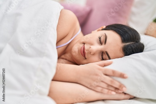 Young hispanic woman lying on bed sleeping at bedroom