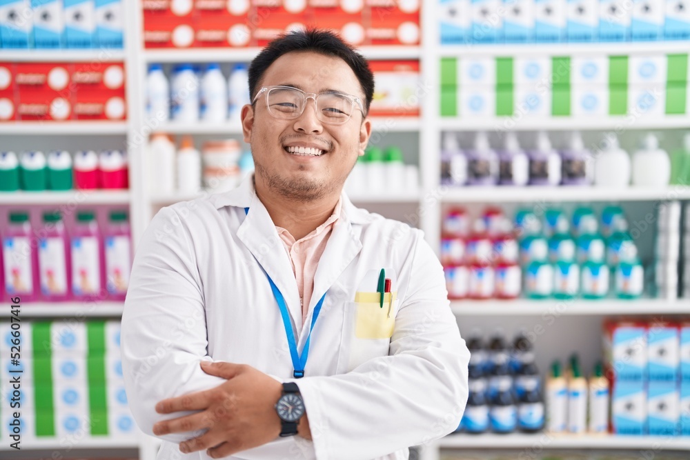 Chinese young man working at pharmacy drugstore happy face smiling with crossed arms looking at the camera. positive person. Chinese young man working at pharmacy drugstore happy face smiling with crossed arms looking at the camera. positive person.