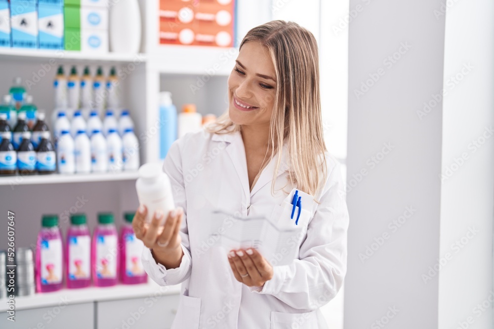 Young caucasian woman pharmacist holding pills bottle reading prescription at pharmacy