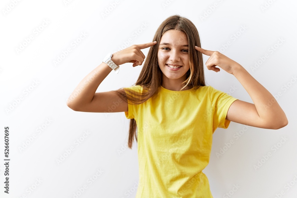 Young brunette teenager standing together over isolated background smiling pointing to head with both hands finger, great idea or thought, good memory Young brunette teenager standing together over isolated background smiling pointing to head with both hands finger, great idea or thought, good memory