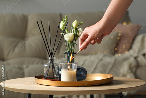 Bild auf Leinwand Woman lighting candle at wooden table in living room, closeup