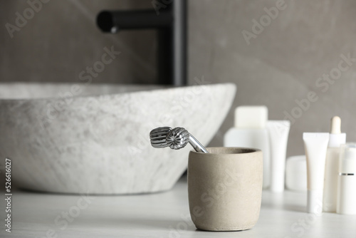 Holder with metal face roller on counter in bathroom. Space for text