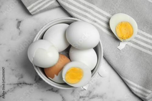 Hard boiled eggs and kitchen towel on white marble table, flat lay