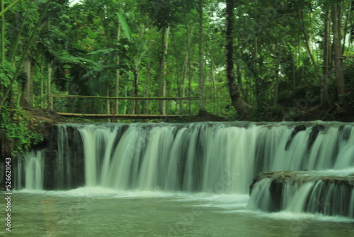 photo of a waterfall in the middle of the forest, a waterfall with clear water