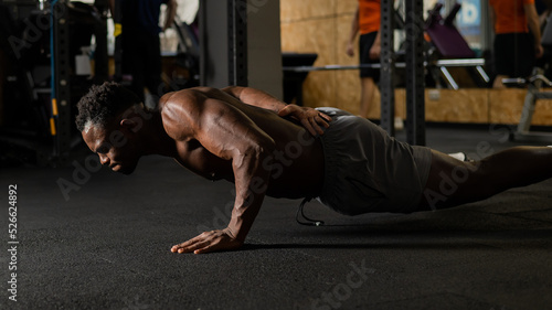 Fototapeta Naklejka Na Ścianę i Meble -  African american man doing one arm push ups in the gym. 