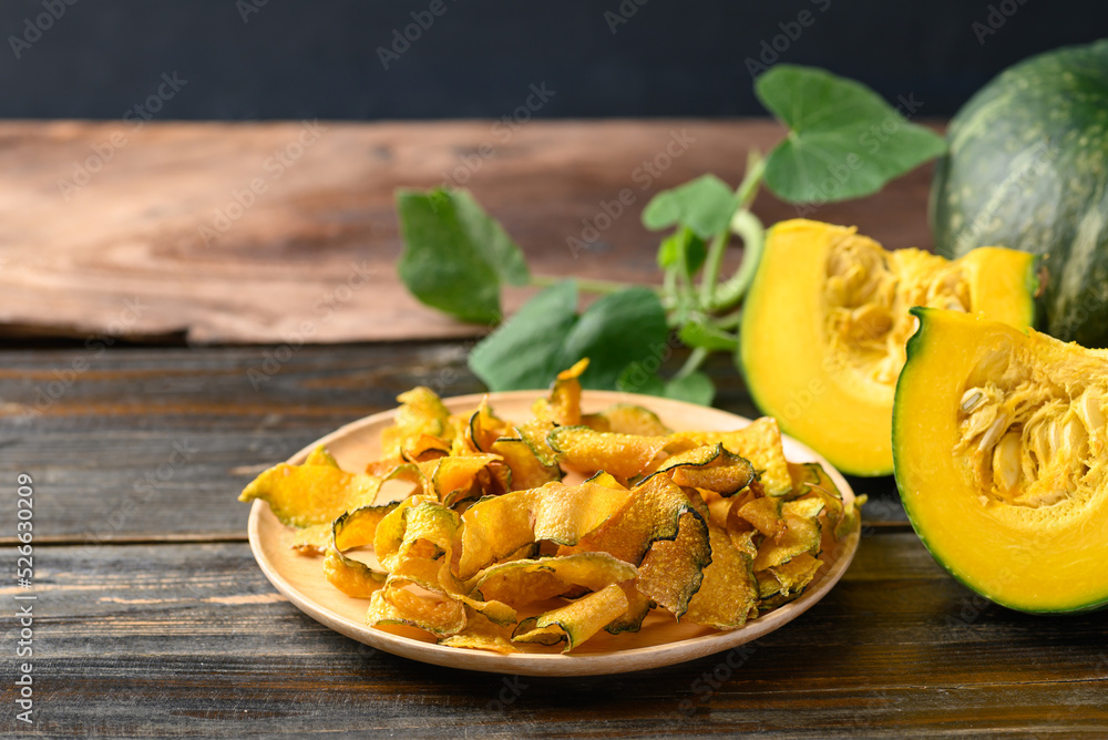 Pumpkin chips on plate with wooden background, Healthy vegan snack Pumpkin chips on plate with wooden background, Healthy vegan snack