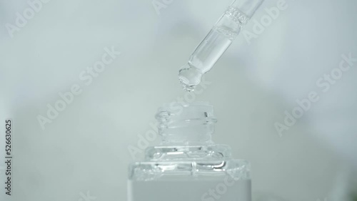 Essential oil blend. Make some fragrance liquid, perfume. Drops fall from the dropper into a small glass bottle on a light blue background