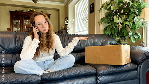 Foto A teenage girl sits in a room and calls on phone she swears at stores from which the parcel was sent next to it there is a box on which you can make an inscription resents delivery was unsuccessful