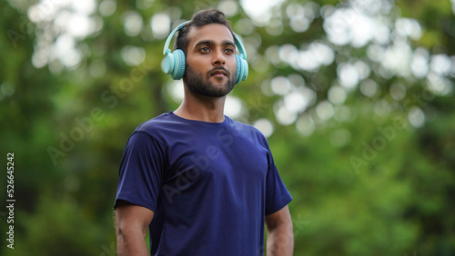 a man standing in the park with headphones in his ear