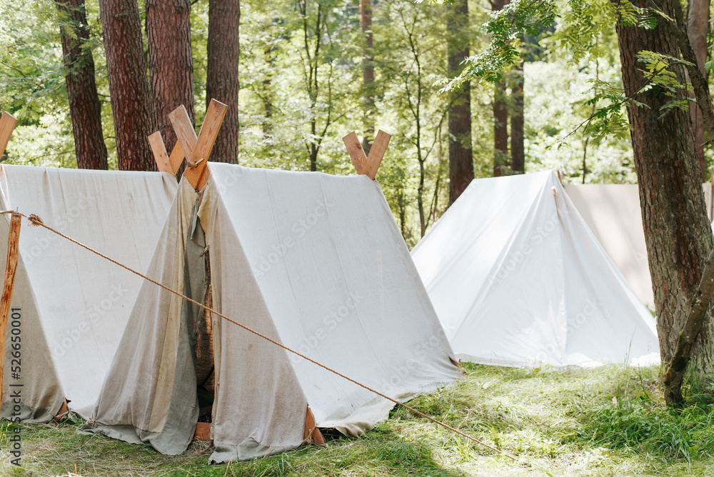 Folk camping lifestyle, reconstruction of life of Middle Ages. Medieval campground in forest, fabric tents on sunny summer day outdoors