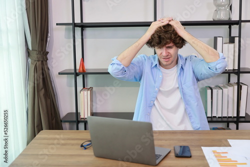 Young adult businesswoman touching his head on table in office after bad news business failure or get fired and feeling discouraged, distraught and hopeless in modern office.