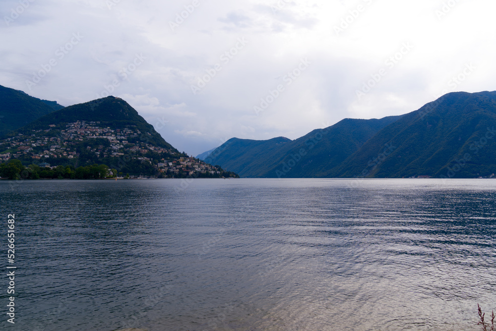 Lake Lugano with local mountain Monte Brè in the background on a cloudy summer day. Photo taken July 4th, 2022, Lugano, Switzerland.