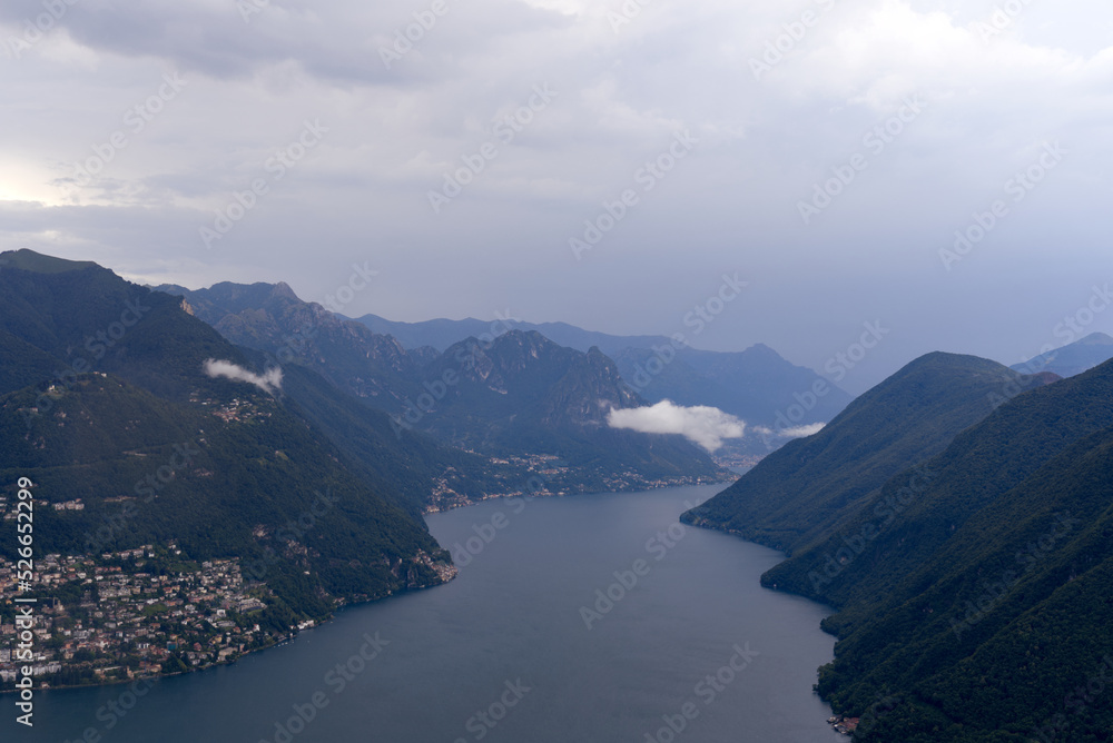 Aerial view from local mountain San Salvatore over region of Lugano, Canton Ticino, with Lake Lugano on a cloudy summer day. Photo taken July 4th, 2022, Lugano, Switzerland.