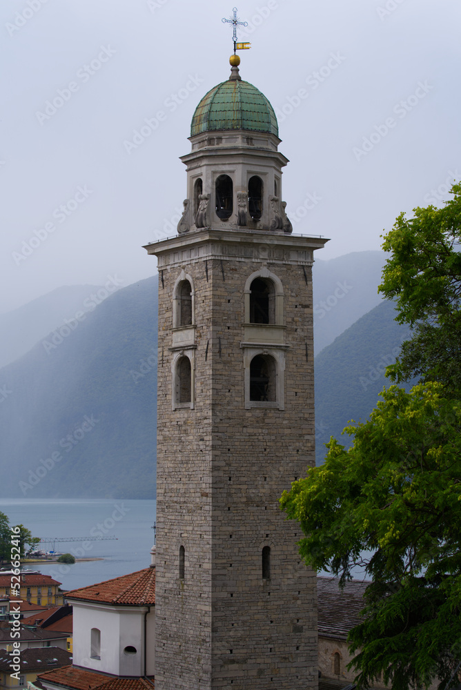 Clock tower of Cathedral San Lorenzo at City of Lugano on a cloudy summer day. Photo taken July 4th, 2022, Lugano, Switzerland.