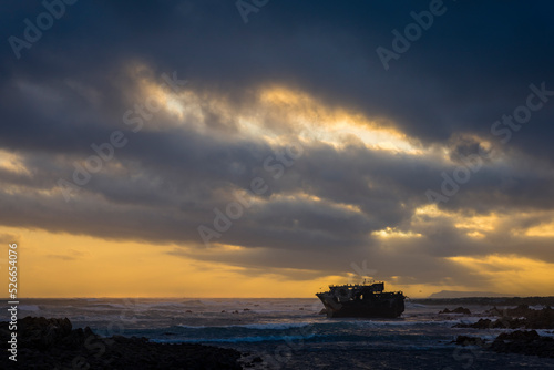 The sun sets beneath a dramatic sky at the wreck of the Meisho Maru No. 38 on the beautiful Cape Agulhas coastline near the seaside town of L'Agulhas in the Overberg, Western Cape. South Africa.
