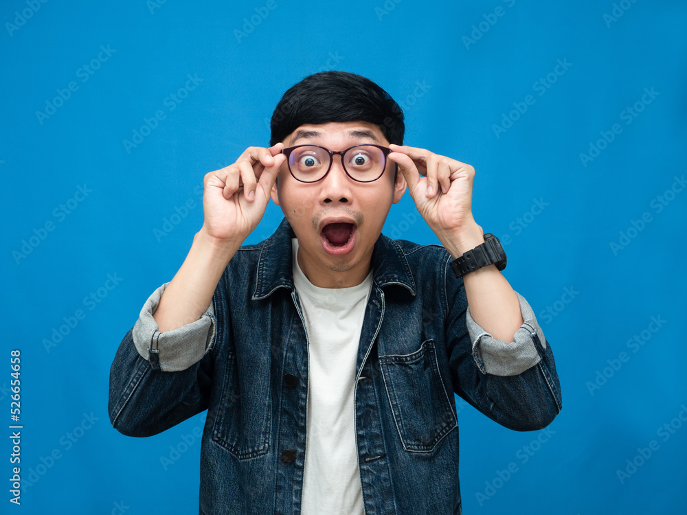 Portrait man jeans shirt feels amazed looking at camera blue background Portrait man jeans shirt feels amazed looking at camera blue background