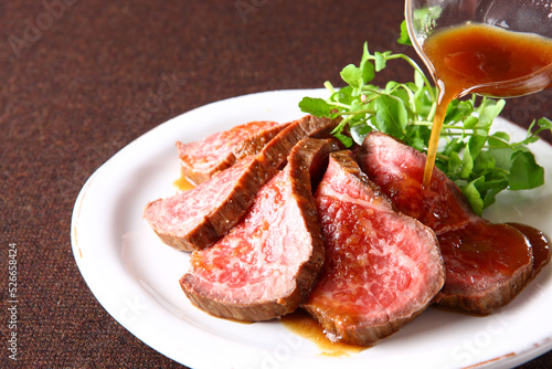 スライスした和牛のローストビーフにローストビーフソースをかけている