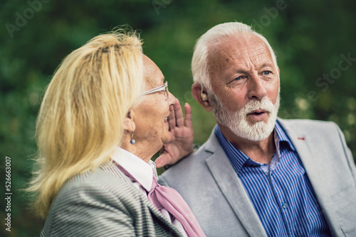 Senior couple with a hearing problem sitting on bench outdoor
