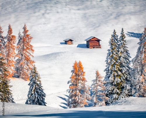 Long foces picture of Alpe di Siusi village. Two wooden chalet on snowy hills in Dolomite Alps. Frosty  outdoor scene of ski resort, Ityaly, Europe. Untouched winter landscape..